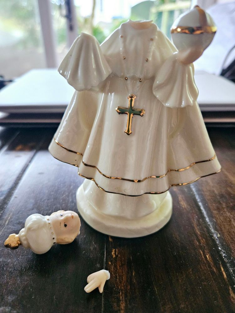 Photo of Child of Prague statue with broken head and hand.