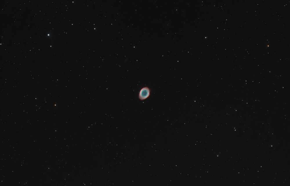 A small, colorful planetary nebula sits nestled amongst a blanket of stars. 