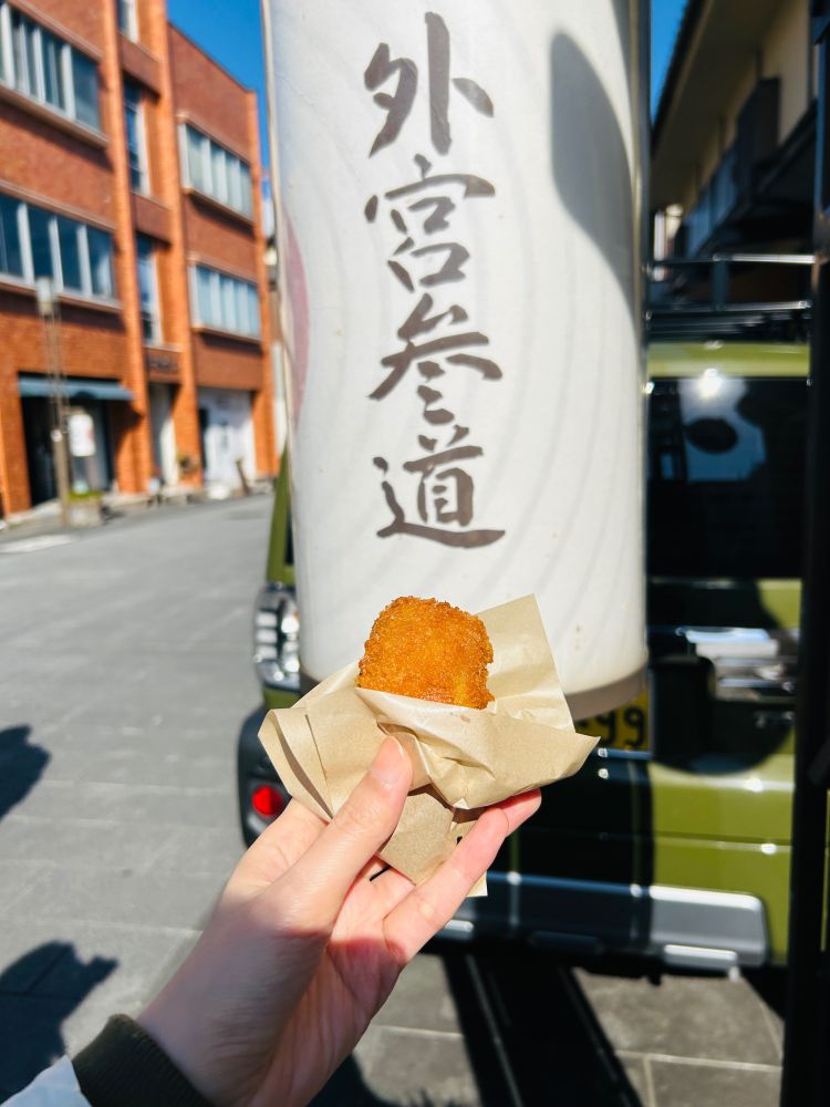 外宮参道と書いてある提灯の前で松阪牛コロッケを持っている。