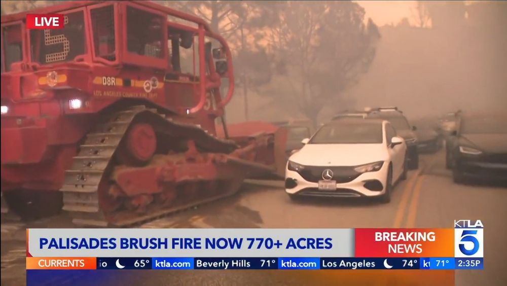 Ktla news screencap reads palisades brush fire now 770+ acres, picture is a big red bulldozer about to plow through a Mercedes and the dozens of cars behind it 