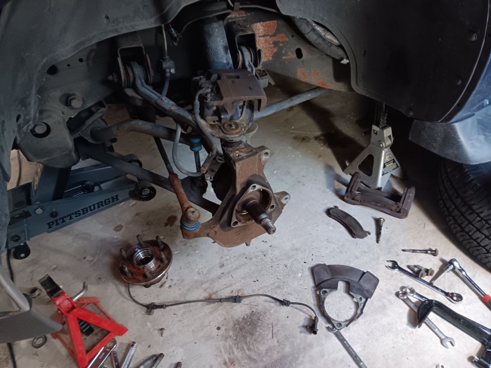 The left front suspension of a GMC Yukon, with the wheel bearing/hub removed for replacement.