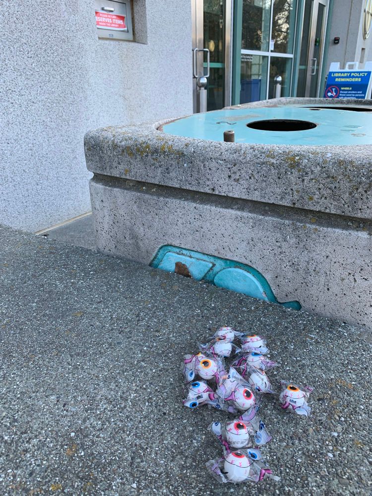 A cluster of a dozen or so individually wrapped bloodshot eyeball candies left on a bench outside of the UC Davis library. 