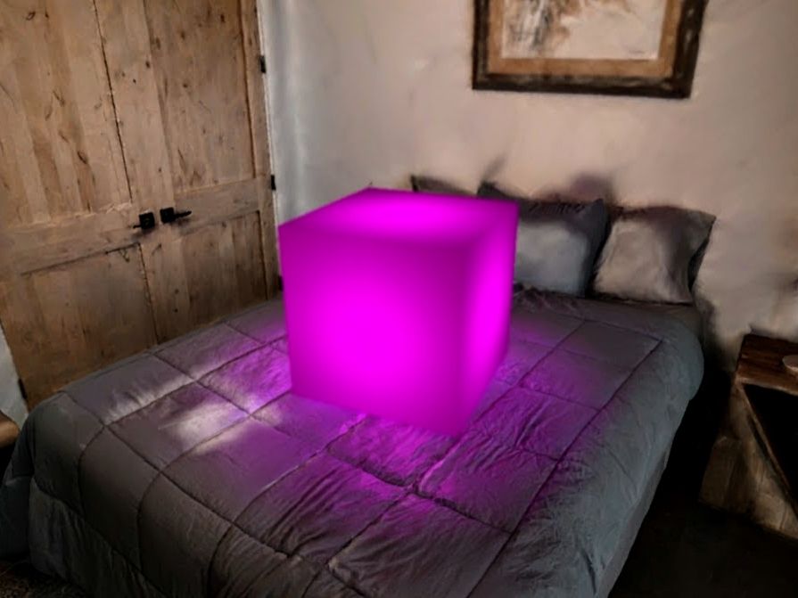 Picture of a large glowing magenta cube resting on a bed
