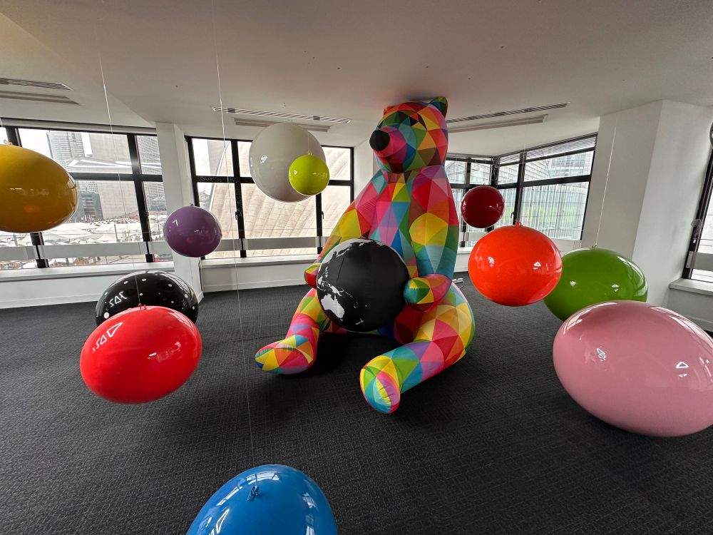 A multi-coloured bear sculptures and various coloured spheres suspended from the ceiling.