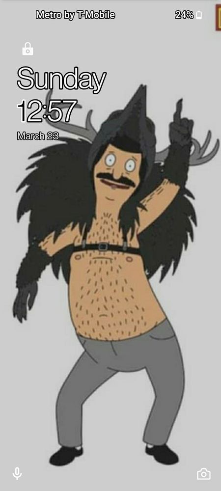 My lock screen, which features Bob from Bob's Burgers. He is dancing, and wearing black clogs, gray pants, no shirt which shows his hairy torso and male presenting nipples, black gloves which resemble bird feathers coming up to his elbows, a set of black raven-like wings affixed via a narrow black band just above his nipples, and a headdress which resembles a raven with antlers.

The time shown is 12:57, Sunday March 23. Battery percentage is 24%