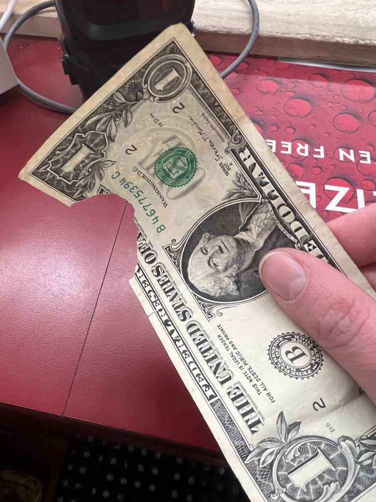 A $1 USD bill with a "bite" taken out of a different spot