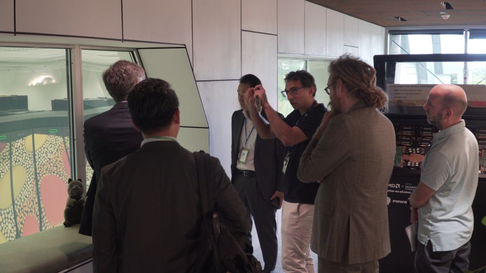 Quantum Supercomputing Researcher Lead Pascal Elahi stands by the viewing window of the Setonix supercomputer, explaining to a group of five men.