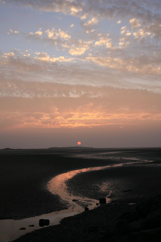 Sunset over West Kirby, with the amber of the sky reflected off the water on the sand banks.