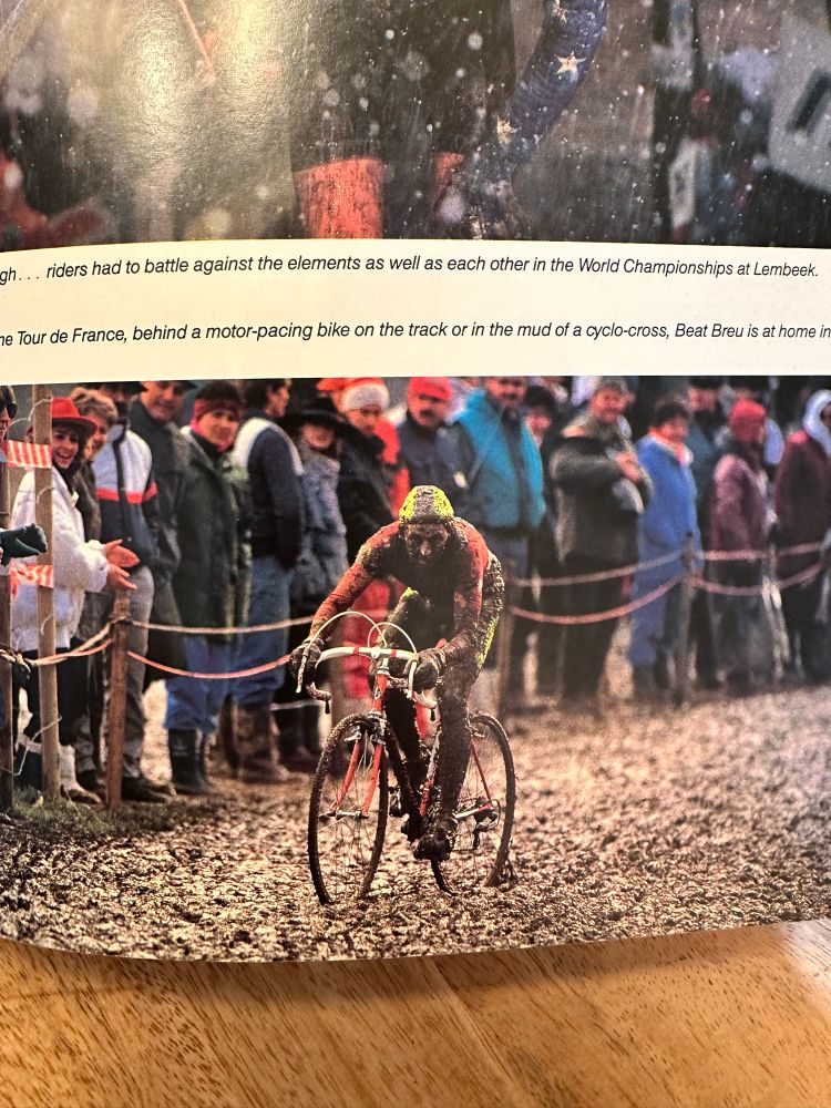Photo of a page in the first edition of Simon Burney’s book, Cyclocross, depicting Swiss cyclist Beat Breu riding a muddy cyclocross race. 