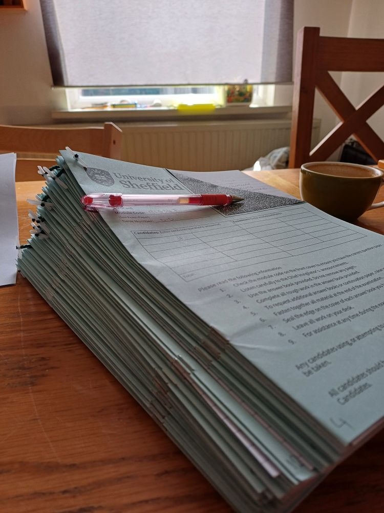 A large stack of exam scripts on my dining room table waiting to be marked