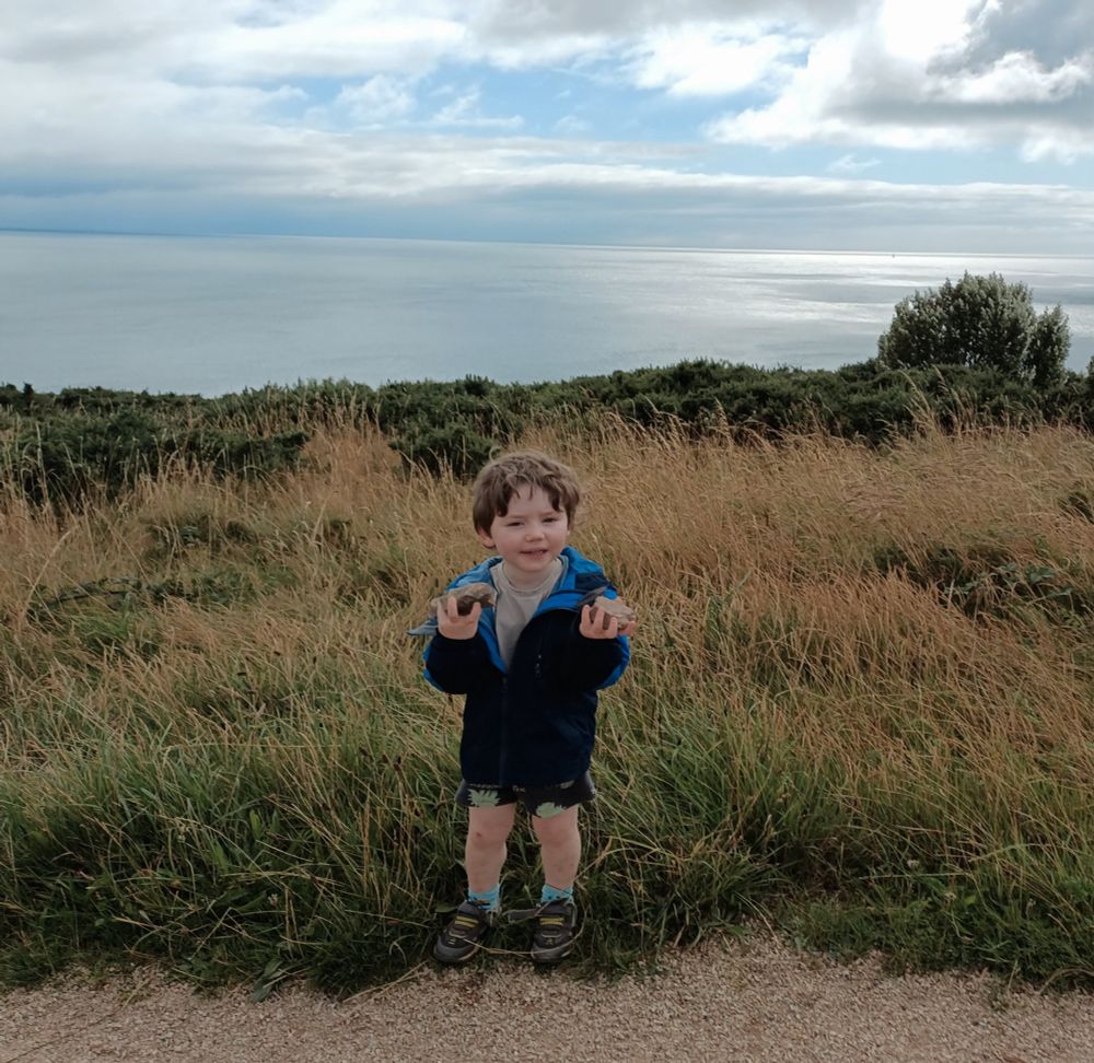 Mr3 standing in some long grass with the Irish sea in the background