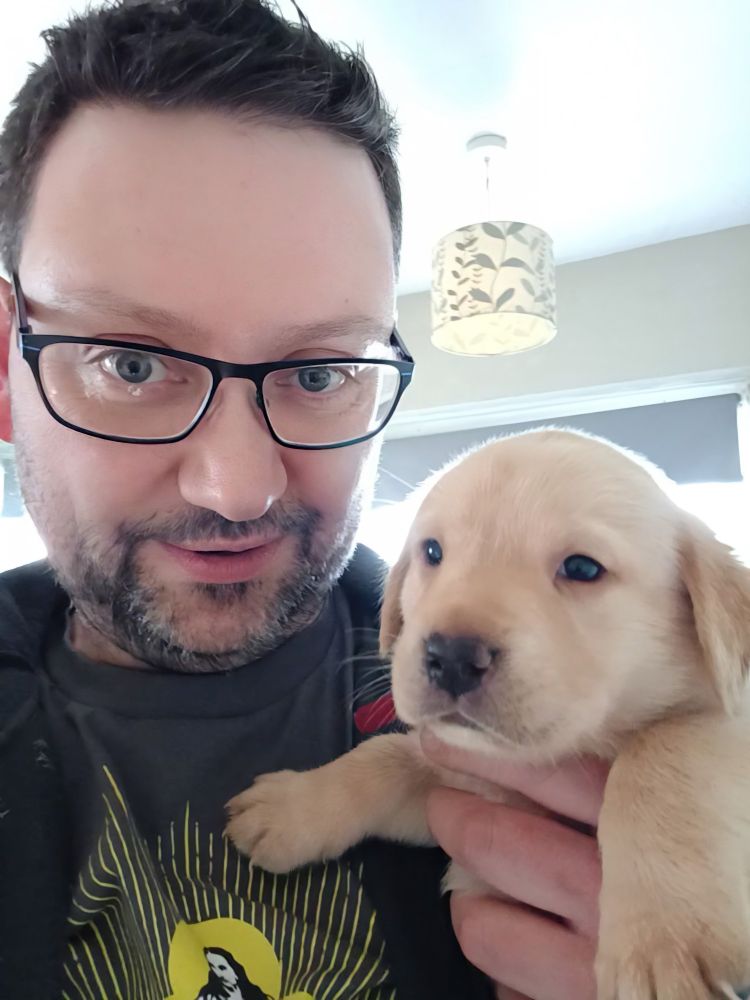 Rob holding a four week old (very fluffy!) yellow Labrador retriever