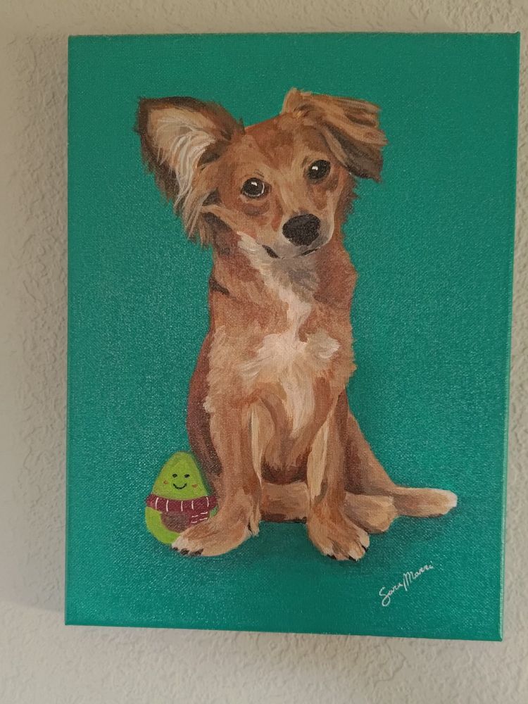 A painting of a little red dog with one ear sticking up tilting his head slightly towards the left in an endearing manner, on a solid teal background. Next to the dog is a small squeaky toy in the shape of a halved avocado, with a smiley face and a red striped scarf.