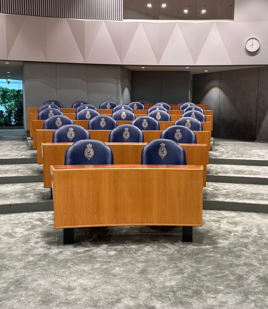 Leeg vak in de Tweede Kamer. Met allemaal lege blauwe stoelen.