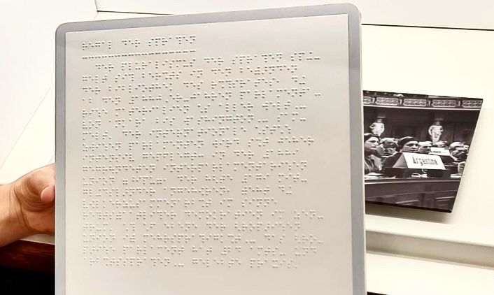 Uitvergroot plakkaat waar ik op de foto het contrast scherper heb neergezet zodat te zien is dat het een braille opdruk heeft. 