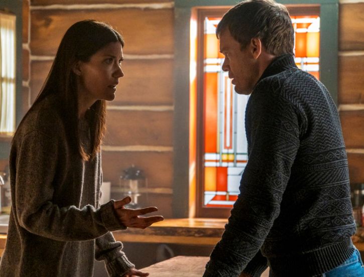 A man and a woman staring at each other while standing in a cabin  