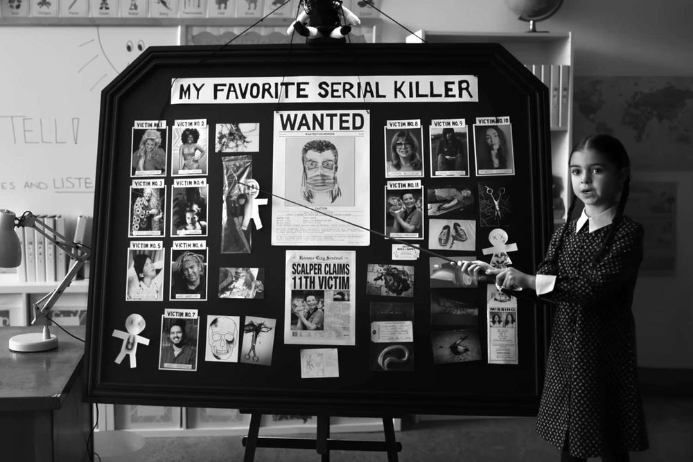 A girl with a presentation board illustrating “my favorite serial killer”