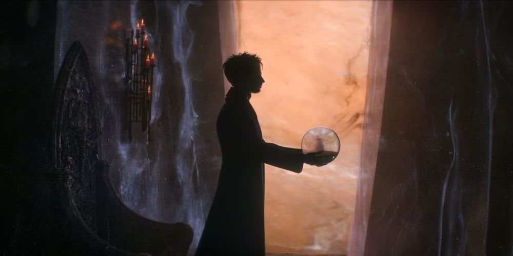 A man holding a glass sphere in his hands in a dark room