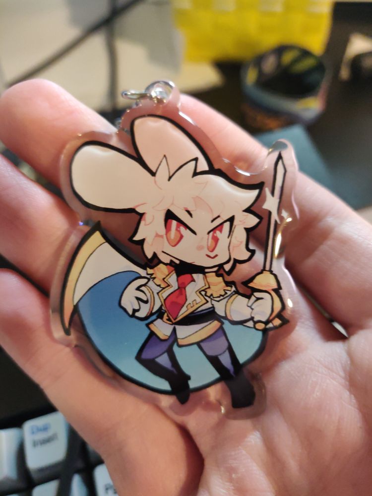a little acrylic charm in my hand. it's a bat wielding a sword.