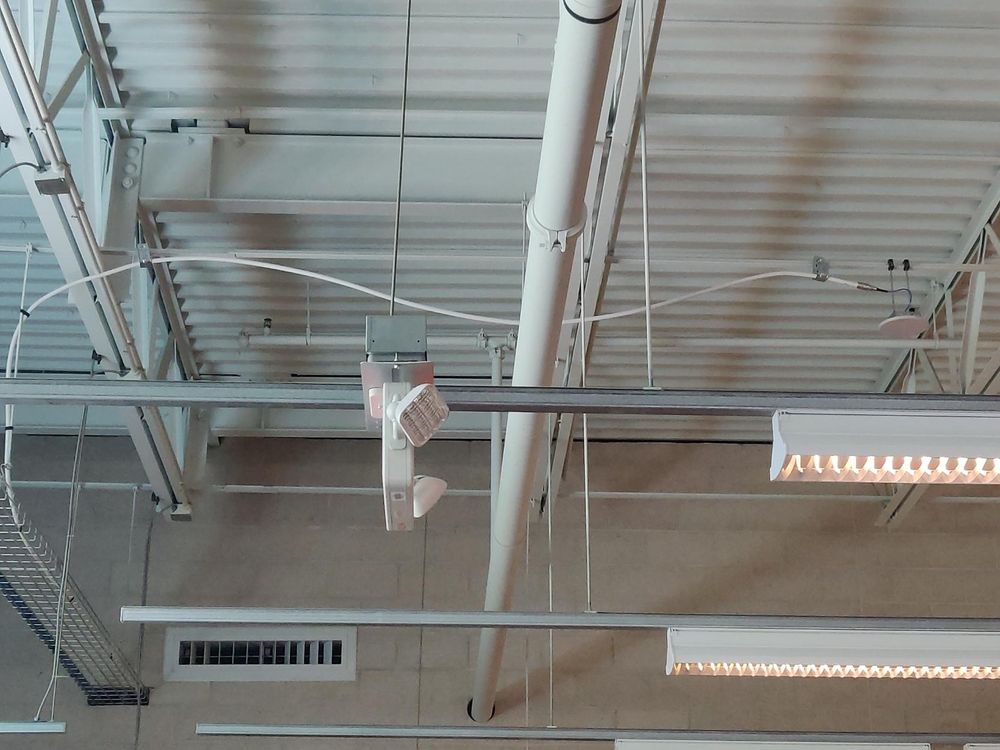 an access point slung under a roof truss, with a little cable connecting it to a long, thicker cable haphazardly floating over to the riser tray