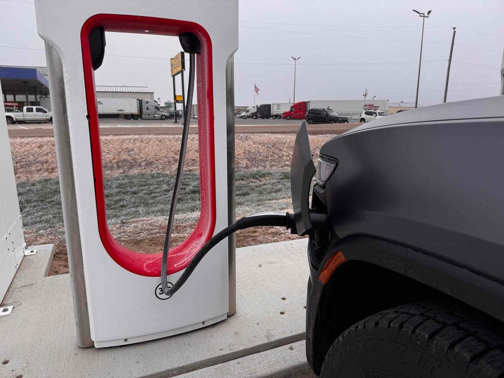 A photo of a Rivian at a Tesla supercharger 