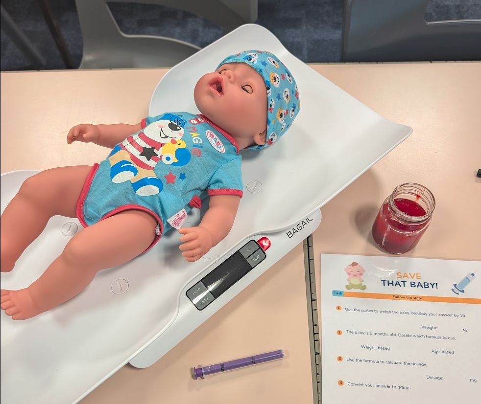 Baby doll on scales, with worksheet and medicine