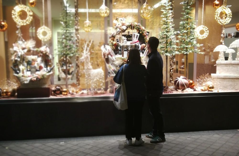 Una pareja mira un escaparate iluminado con motivos navideños