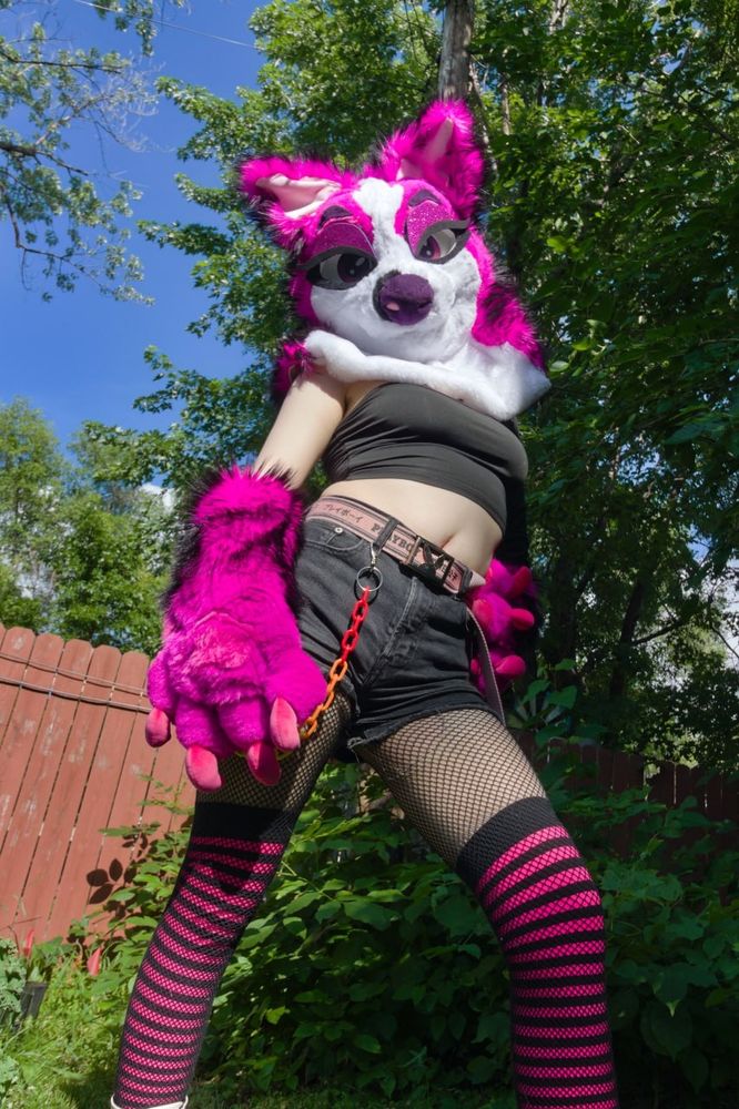 Outdoor photo of cherry the pink puppy fursuit partial.