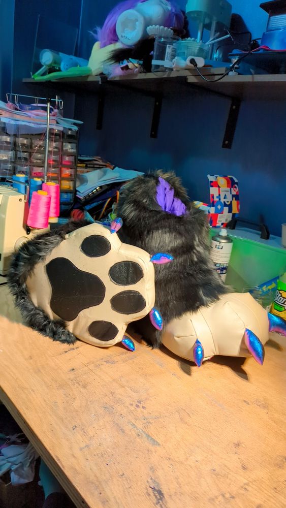 Shows new feet paws that have shiny metallic claws, faux leather toe beans on dark brown, and peach faux leather soles and toes. The main fur is a deep grey.
One is on its side to show the sole of the feet, the other stands