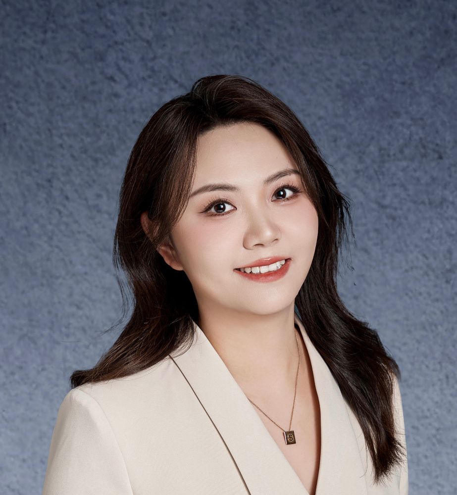 Tiffany Sheng has long black hair and is wearing a white suit jacket with a necklace.