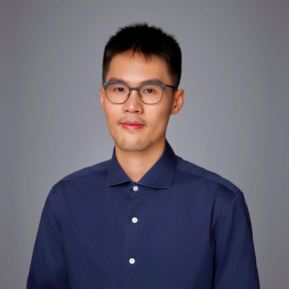 Tao Li has short black hair, glasses, and is wearing a dark blue button-down shirt.