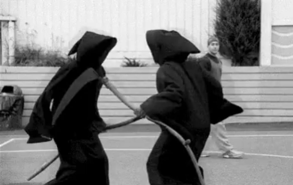 a black and white photo of two grim reapers holding scythes .