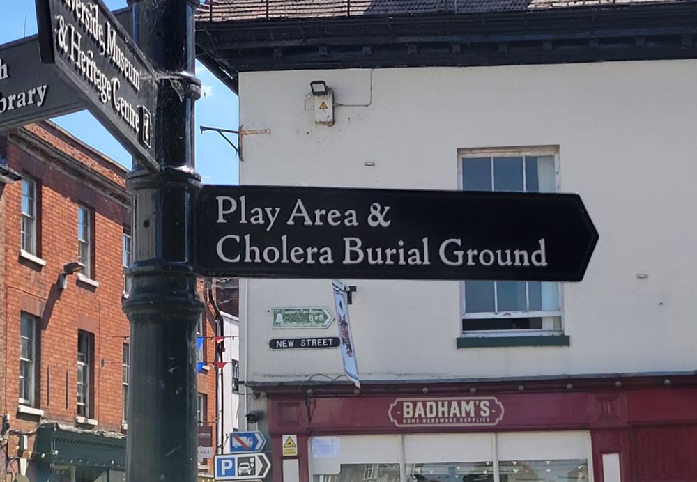 A street sign in Upton, England reading "Play Area and Cholera Burial Ground"