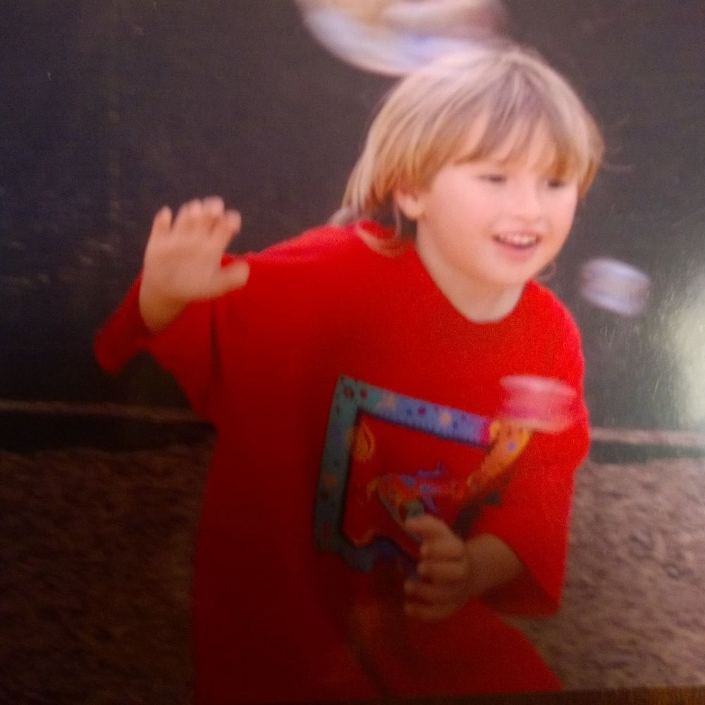Me as a child with blond hair , a red shirt and oveily happy