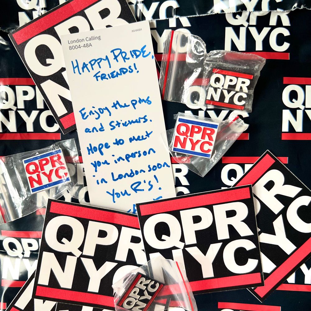 A selection of badges and stickers from QPR NYC. An accompanying notes reads, “Happy Pride friends!”