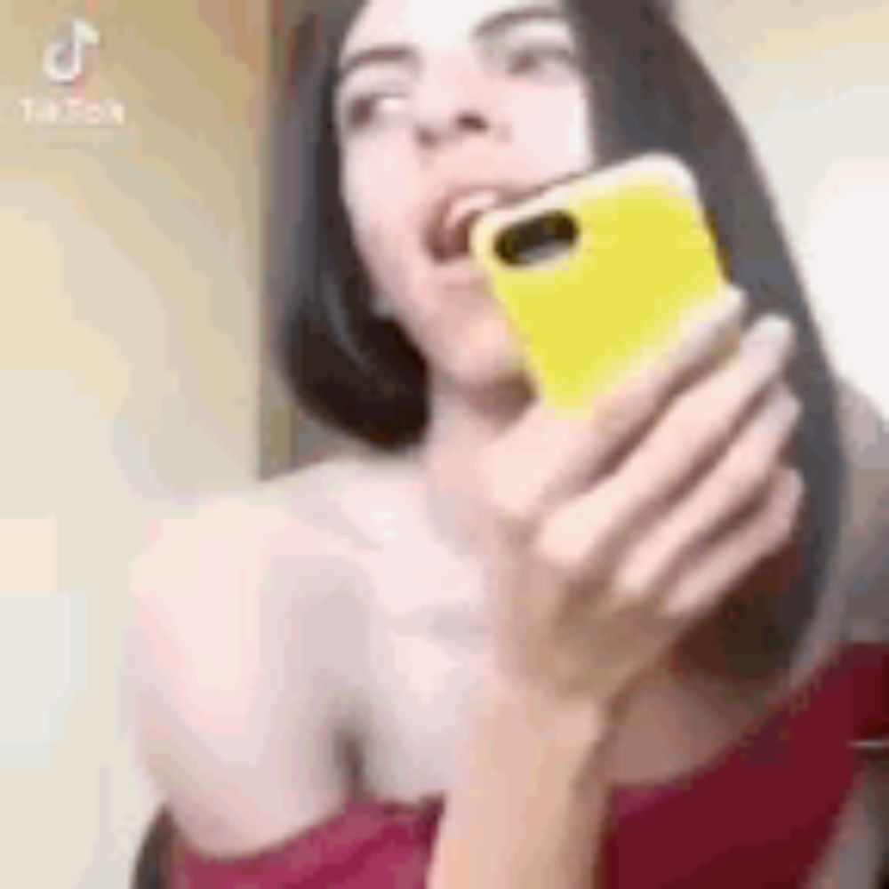 a woman is holding a cell phone in her hand and making a funny face .