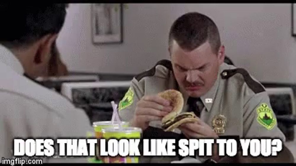 a man in a sheriff 's uniform is eating a hamburger with the caption does that look like spit to you ..