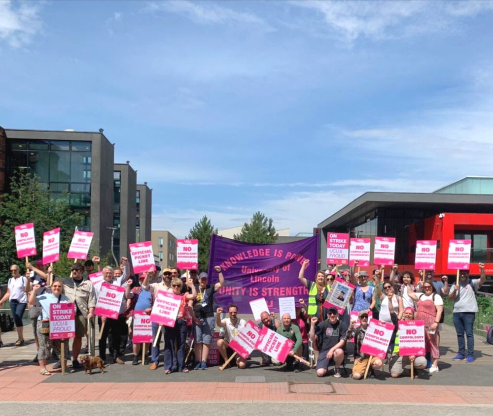 About 40 striking academics posing by a banner: “Knowledge is Power, Unity is Strength, University of Lincoln UCU”
