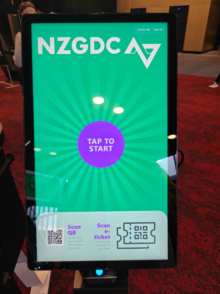 A touch screen saying NZGDC and tap to start