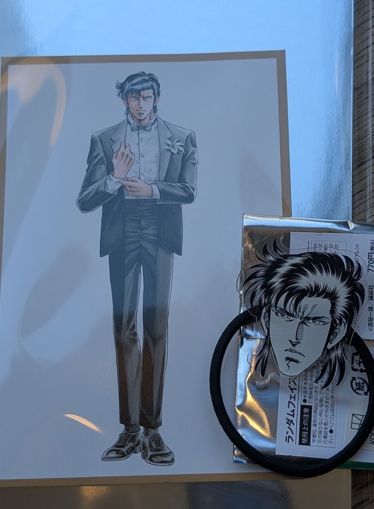 真船一雄原画展Kの系譜入場特典のポストカードと、フェイスヘアゴムの写真
どちらも一人先生