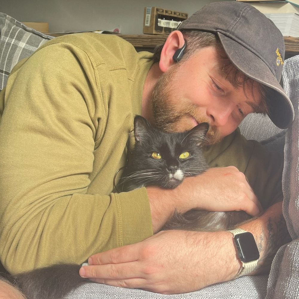 a beautiful black and white tuxedo cat tolerating a bear hug from her obsessed human