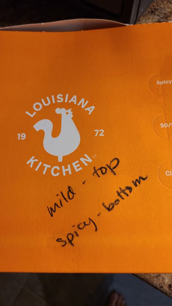 A box of Popeye's Chicken with a hand written note that reads 
"mild - top
spicy - bottom"