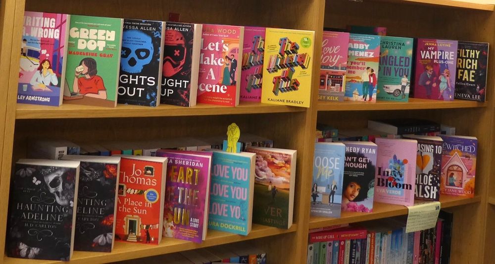 Photo of romance themed books facing out on a few shelves. A range of new and recent titles from HD Carlton, Jo Thomas, Mia Sheridan, Navessa Allen, Kaliane Bradley, Abby Jimenez, Kennedy Ryan among others.