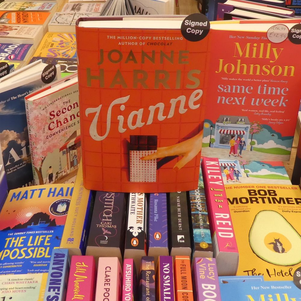 Photograph of hardback book of Vianne, Joanne Harris, sitting on top of other books. I have a copy at home, this is one of our signed copies in store.