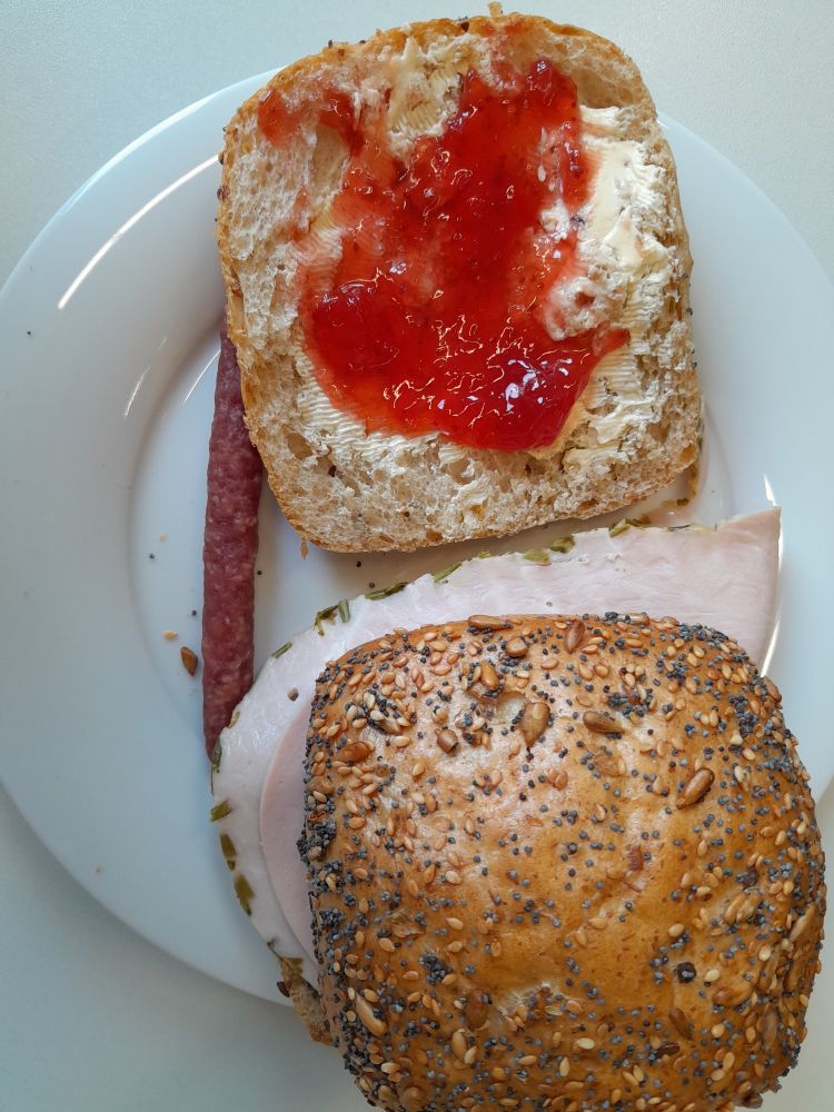 Two rolls: one with strawberry jam and one with ham, and a small salami