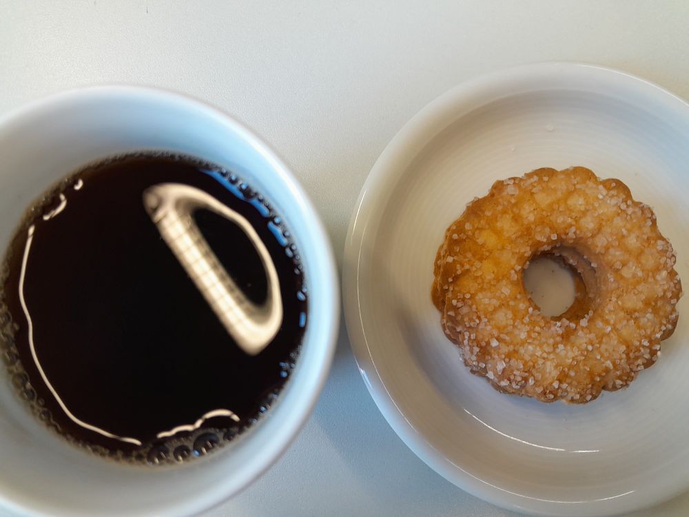 Bird's eye view of a cup of black tea and a biscuit 