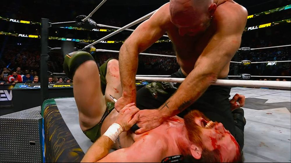 Jon Moxley stabbing Kyle O'Reilly's nipple with a fork.