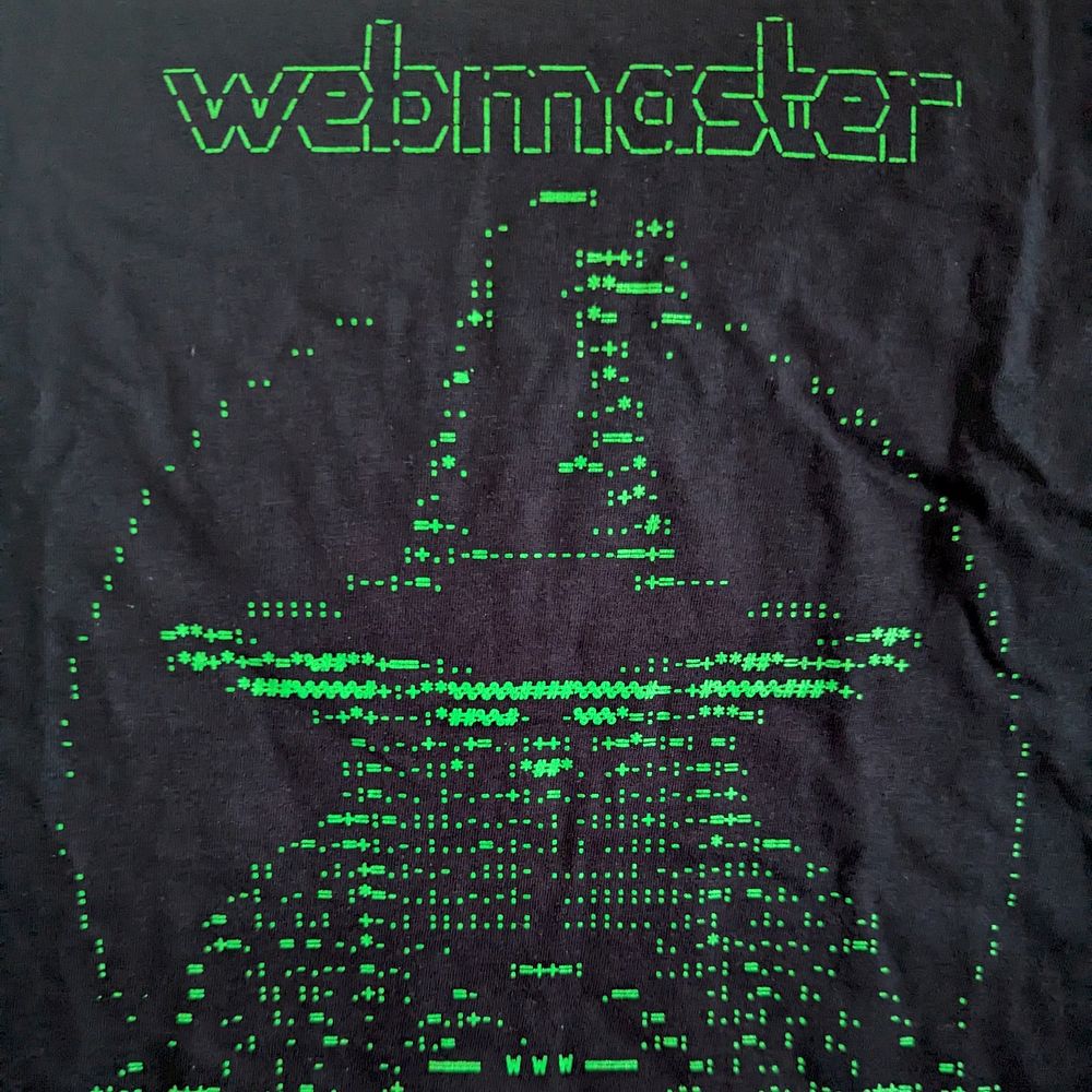 A black t-shirt with small, green ASCII characters similar to an old computer screen. Together the characters create a picture of a wizard with the word 'webmaster' above it