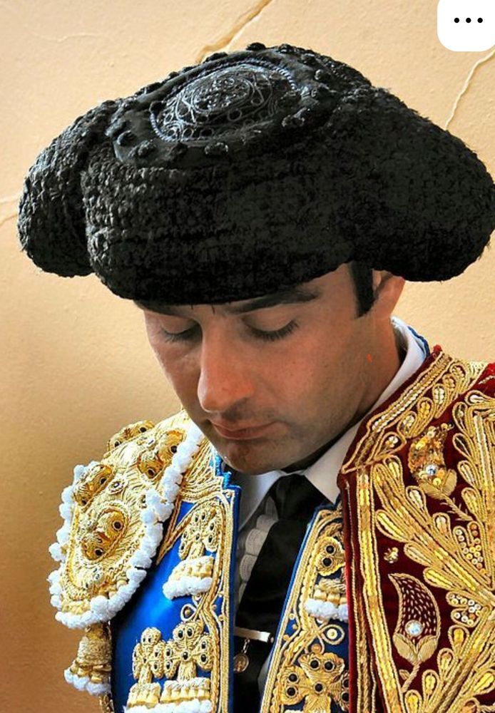 A headshot of a Matador in the traditional suit of lights looking down.