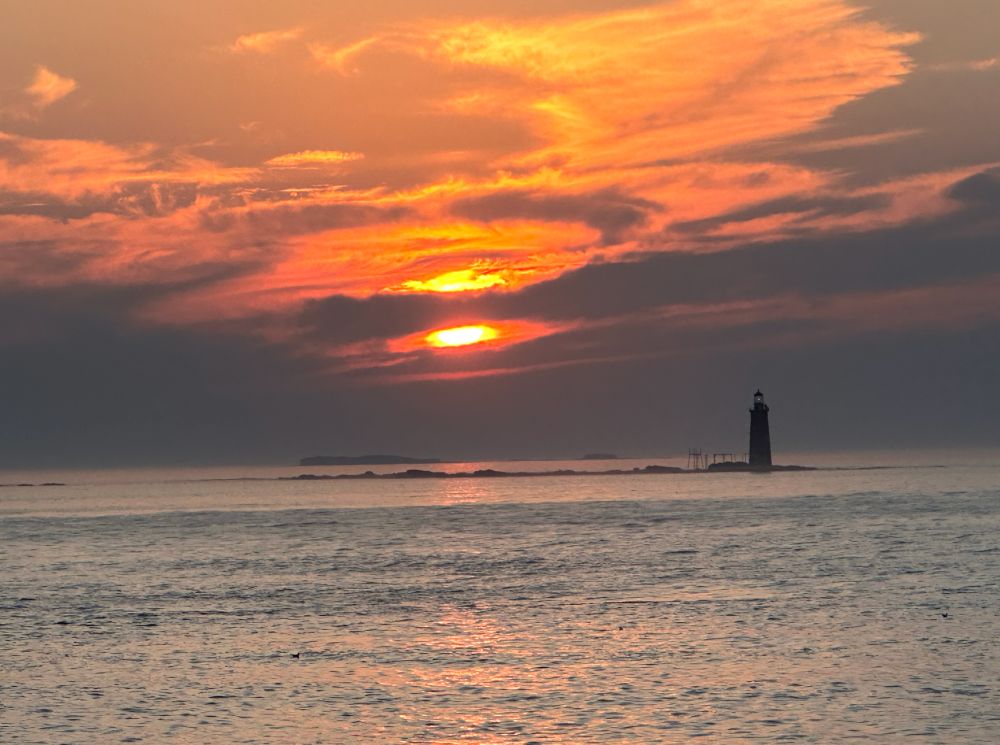 sunrise over ocean next to lighthouse. Somewhere off the coast of Maine. 